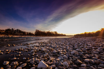 Surface level of stones on shore against sky during sunset