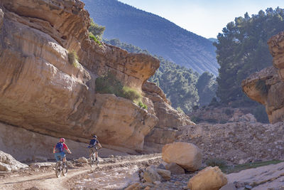 Rear view of people cycling at mountains