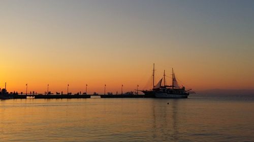 Silhouette sailboats in sea against sky during sunset