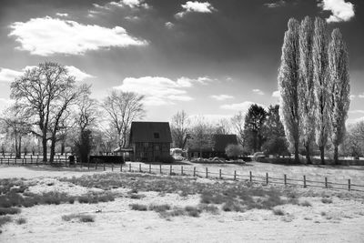 Built structure on field by trees against sky
