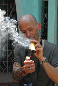 Man igniting cigar against wall