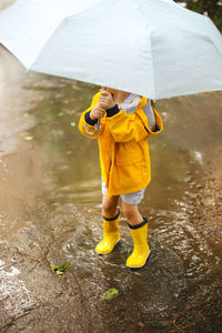 High angle view of girl holding umbrella standing on road