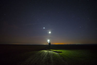 Silhouette person standing on field against sky at night