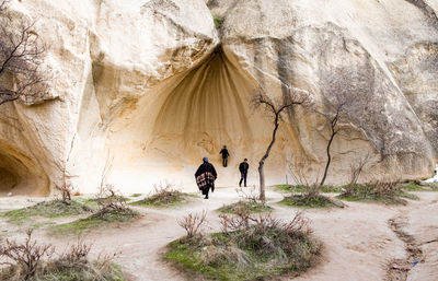 Rear view of people walking on rock