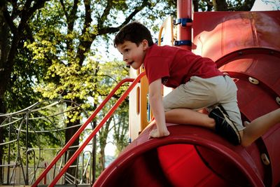 Boy climbing on tunnel slide in playground