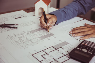 Midsection of man working on blueprint