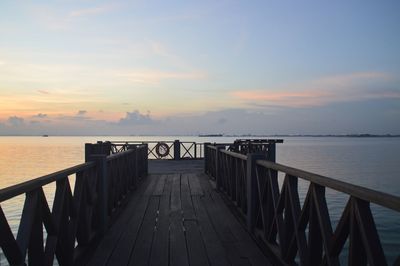 Pier over sea against sky during sunset