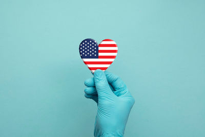 Close-up of hand holding umbrella against blue background