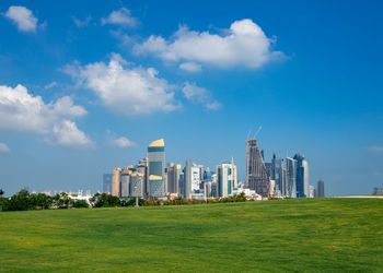 Buildings on field against blue sky