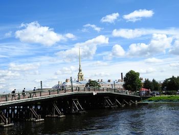 Bridge over river in city against cloudy sky