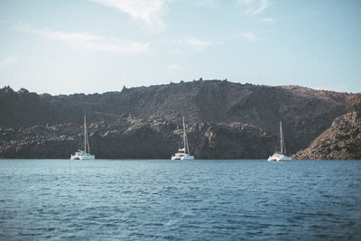 Sailboats sailing on sea against sky