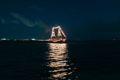 Illuminated ship in sea against sky at night
