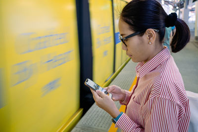 Side view of young woman using mobile phone