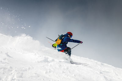 Skiing, skier, frisky - freeride, a man is stylishly skiing on a snowy slope with snow dust plume