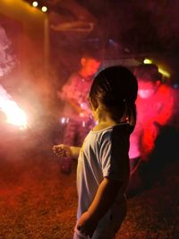 Rear view of girl with arms outstretched standing at night