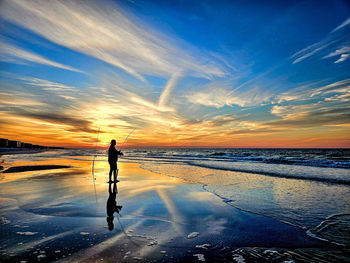 Fisherman surf fishing on coast of florida at sunrise.