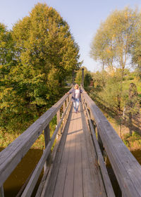 Footbridge over footpath amidst trees against sky