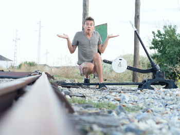 Portrait of shocked young man crouching by railroad switch stand