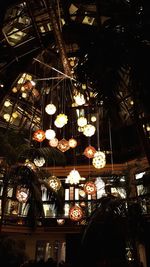 Low angle view of illuminated lighting equipment hanging at night