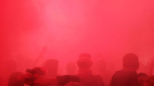 Group of people on pink road against clear sky at night