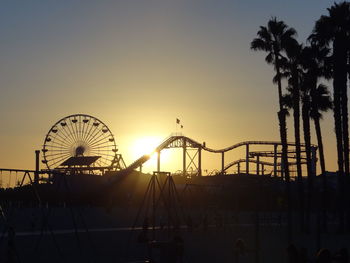 Silhouette ferris wheel against clear sky at sunset