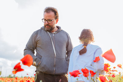 Father and daughter standing in the poppy field on a sunny day