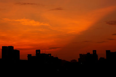 Silhouette city against orange sky