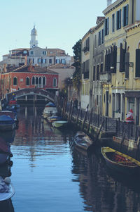 Boats moored at canal against buildings in city