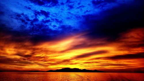 Scenic view of sea against dramatic sky during sunset