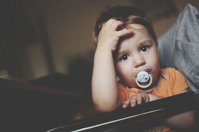 Portrait of cute with pacifier in mouth at home