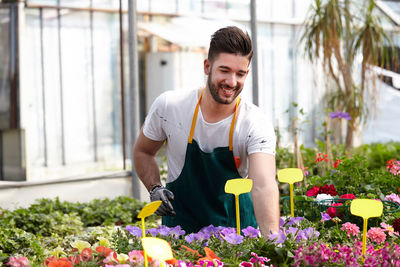 Smiling young man standing by flowering plants