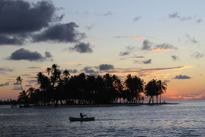 Silhouette of a person paddling against a dreamlike island