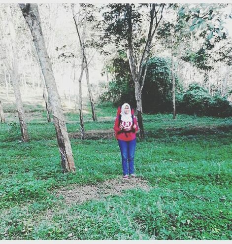 tree, grass, lifestyles, full length, casual clothing, standing, leisure activity, green color, growth, rear view, day, plant, nature, field, tree trunk, front view, walking, tranquility