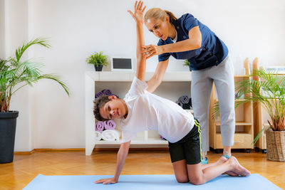 Lateral flexion exercise for children. boy exercising with physical therapist.