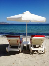 Deck chairs on beach against clear blue sky