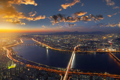 High angle view of illuminated city against sky during sunset