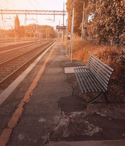 Empty bench by railroad station platform