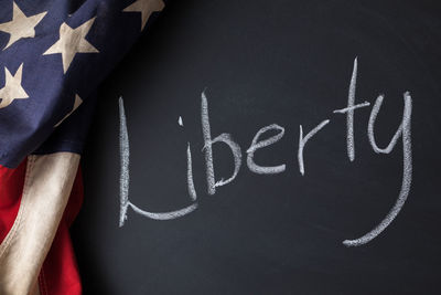 Close-up of american flag with text on blackboard