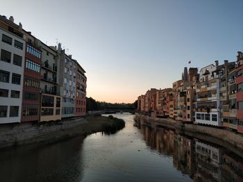 River amidst buildings against sky during sunset