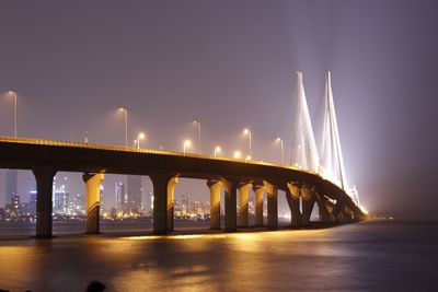 Bridge over calm river against clear sky