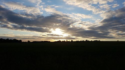 Scenic view of silhouette field against sky during sunset