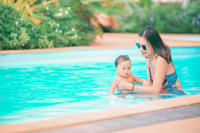 Rear view of mother and daughter in swimming pool