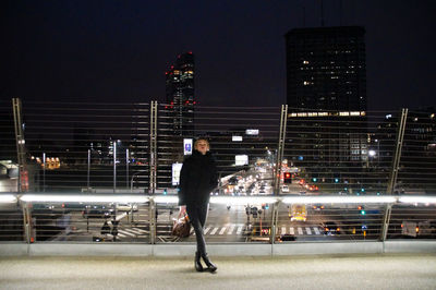 Full length of man standing on illuminated road against sky at night
