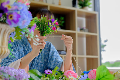 Woman tying flowers with string at home