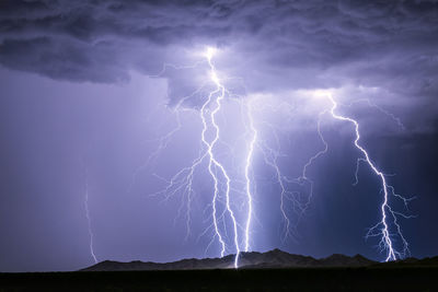 Lightning bolts strike a mountain as a thunderstorm drifts through the desert near phoenix, arizona. 