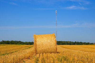 Hay bales on field against sky