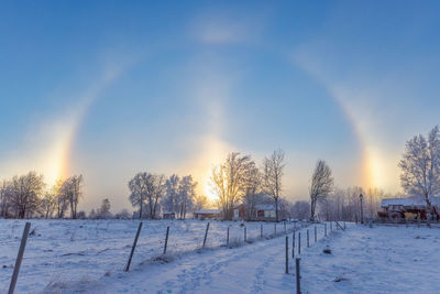 Snow covered field against sky during sunset