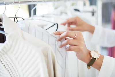 Hands of woman choosing cloth form rack in store