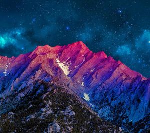 Low angle view of mountain range against starry sky