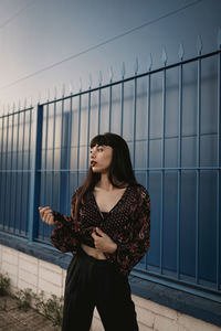 Young woman looking away while standing on railing